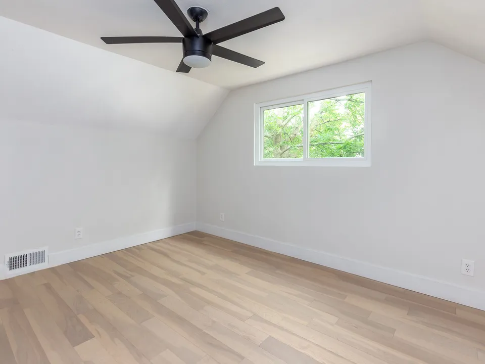 Upstairs bedroom with a sloped ceiling and light wood floors