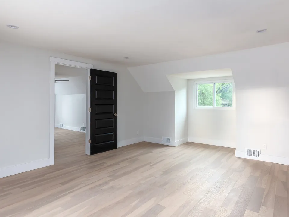 Upstairs room with a black door and a dormer window